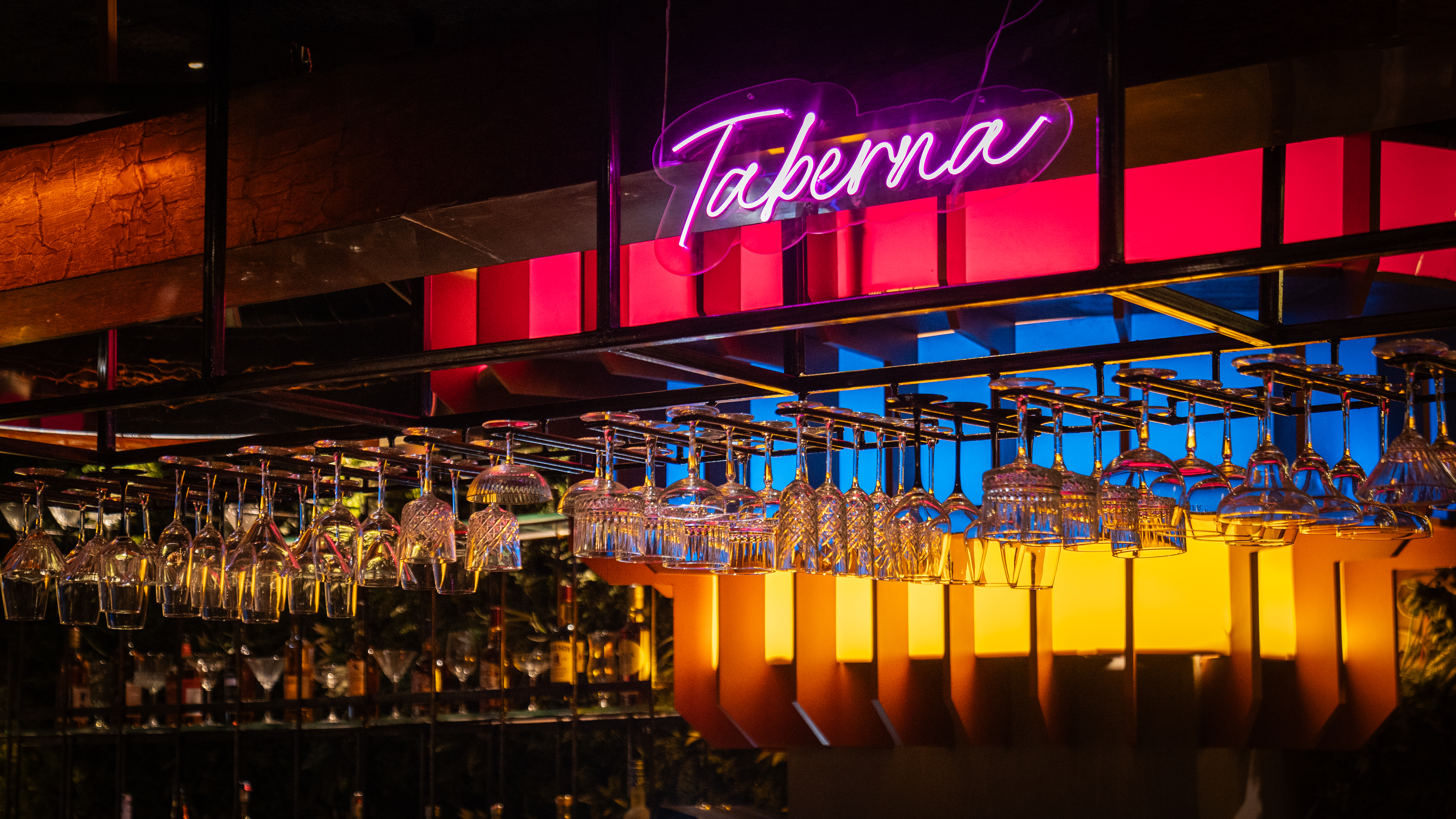 Bar with neon Taberna sign and hanging glasses